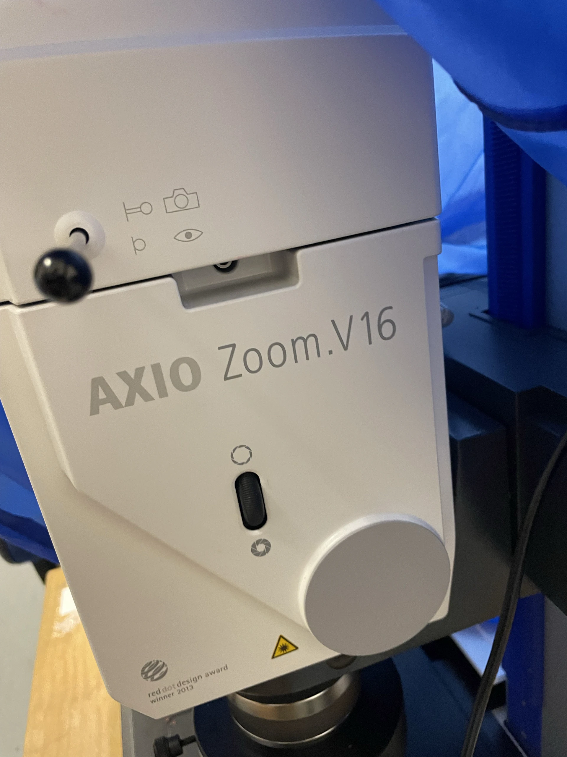 Close-up of the Zeiss AXIO Zoom.V16 microscope head with blue drapes behind