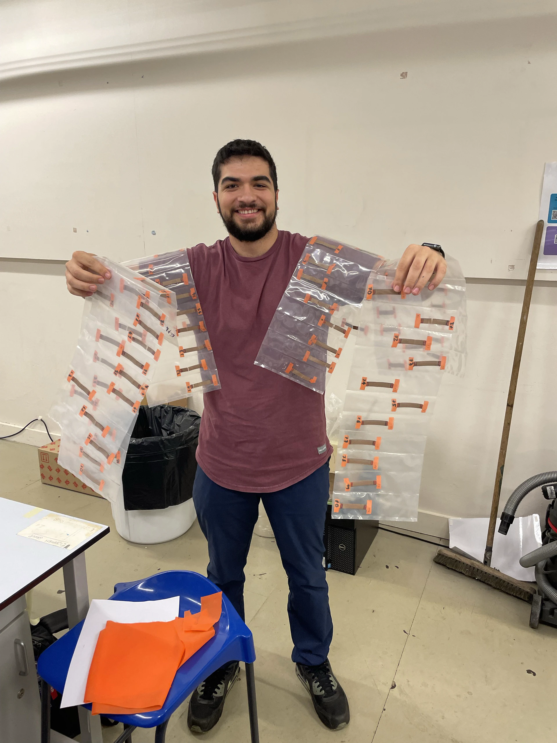 Bagged and labelled humidity-conditioned specimen batches held up in the lab, each strip tagged with orange tape