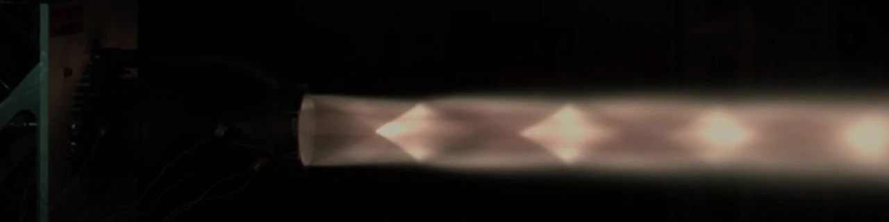 Single 1000 fps frame of the Test 3 plume, diamonds visible as bright knots in a pale exhaust against a dark cell