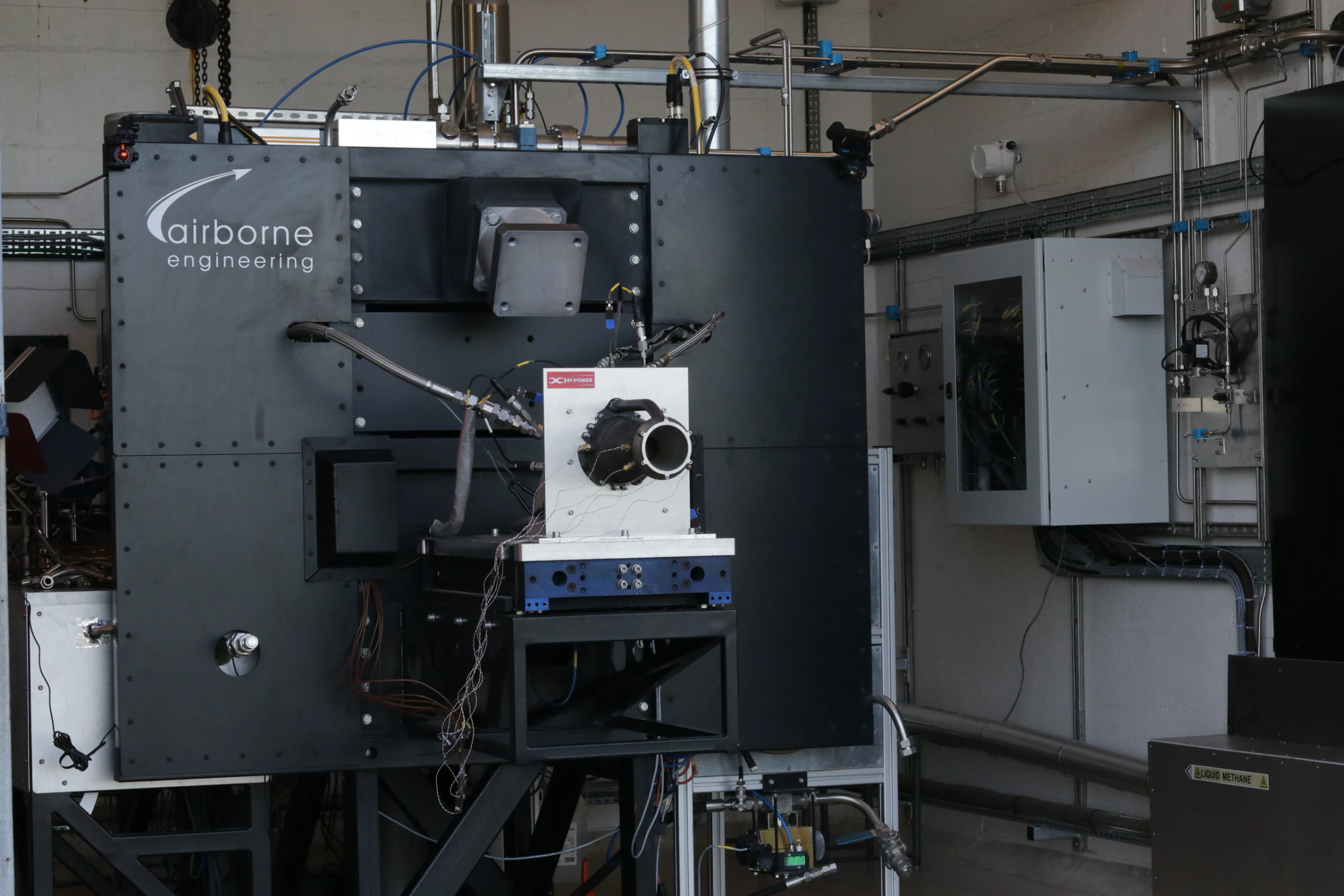 Wide view of the AEL test cell with Engine 1 mounted on the thrust stand in front of the blue Airborne Engineering instrumentation wall