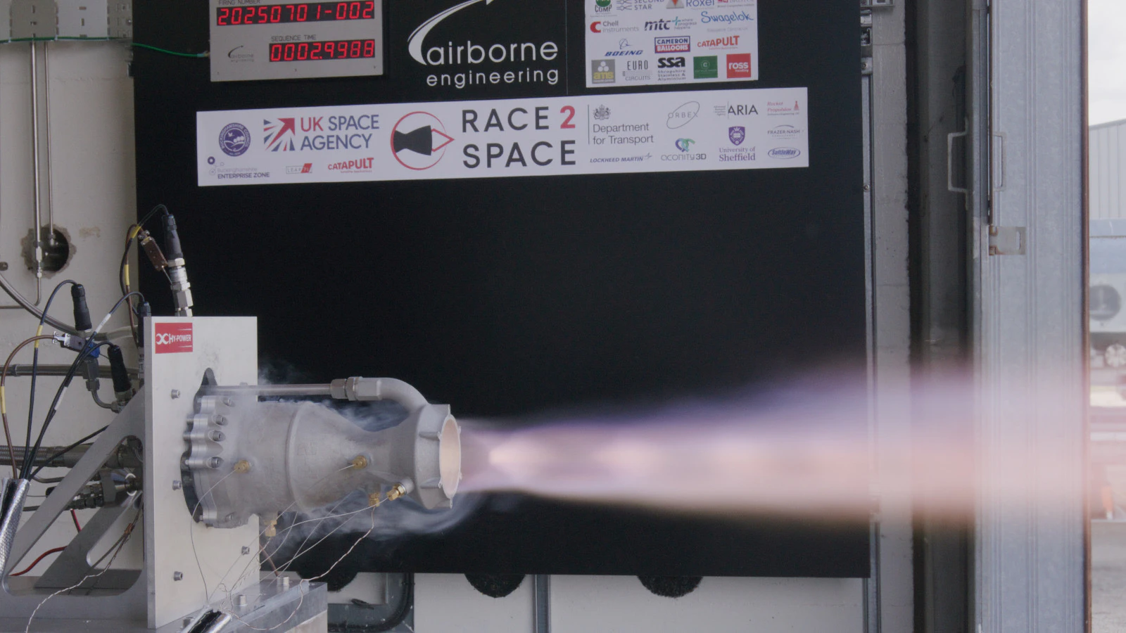 Engine 2 on the AEL thrust stand at T+3.0 s with a purple plume streaming from the nozzle, sequence timer and firing number visible