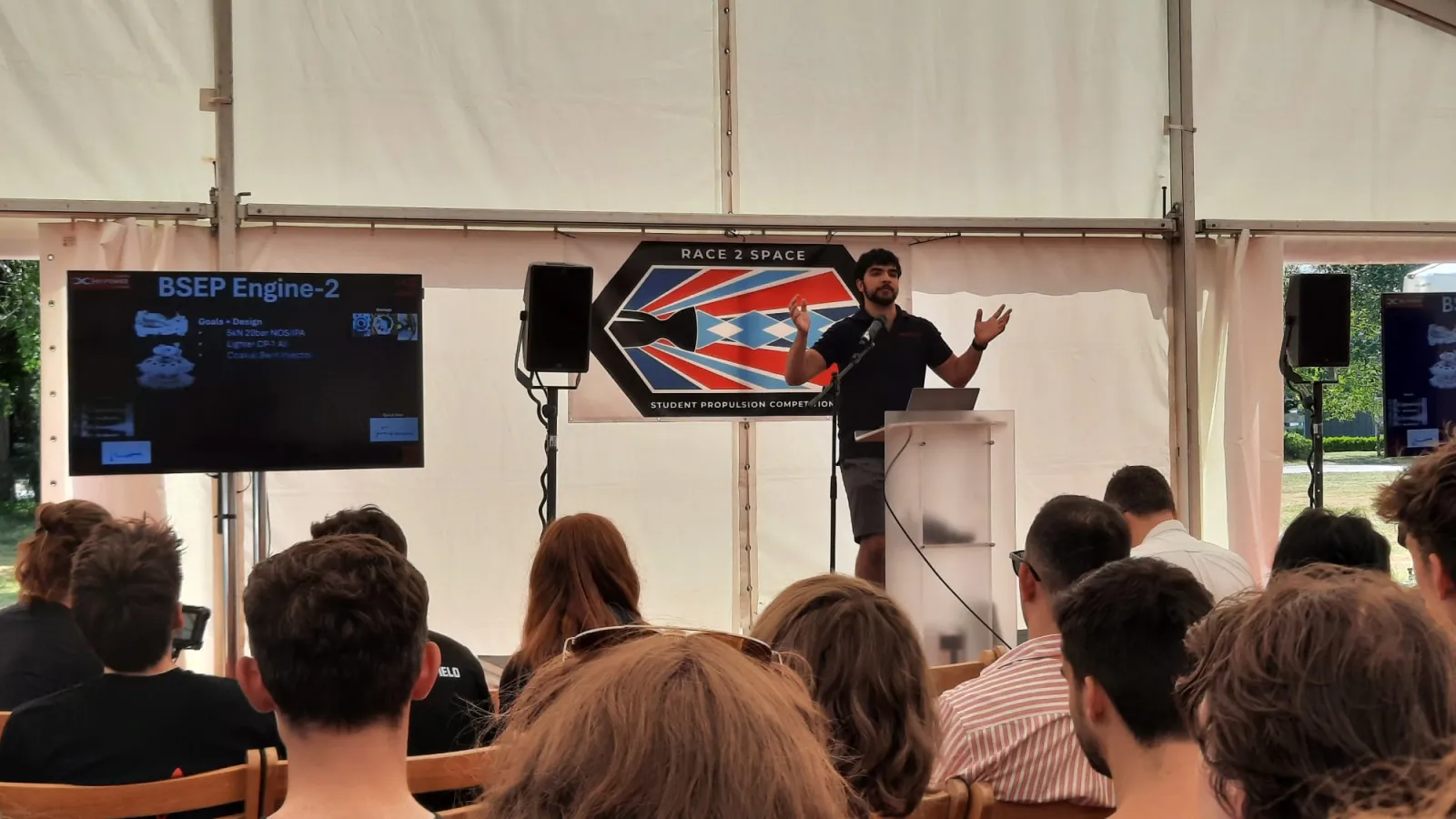 Ethan presenting Engine 2 results to a seated audience in the Race 2 Space marquee