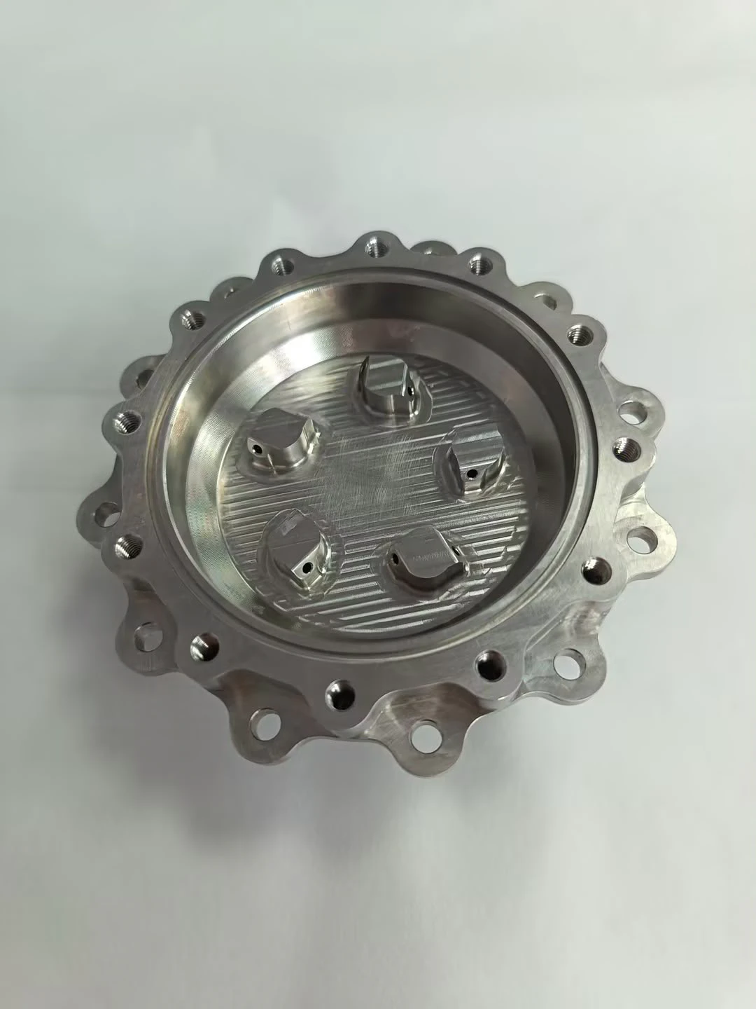 Reverse side of the injector body with five machined element seats inside the bore and a lobed flange with threaded holes