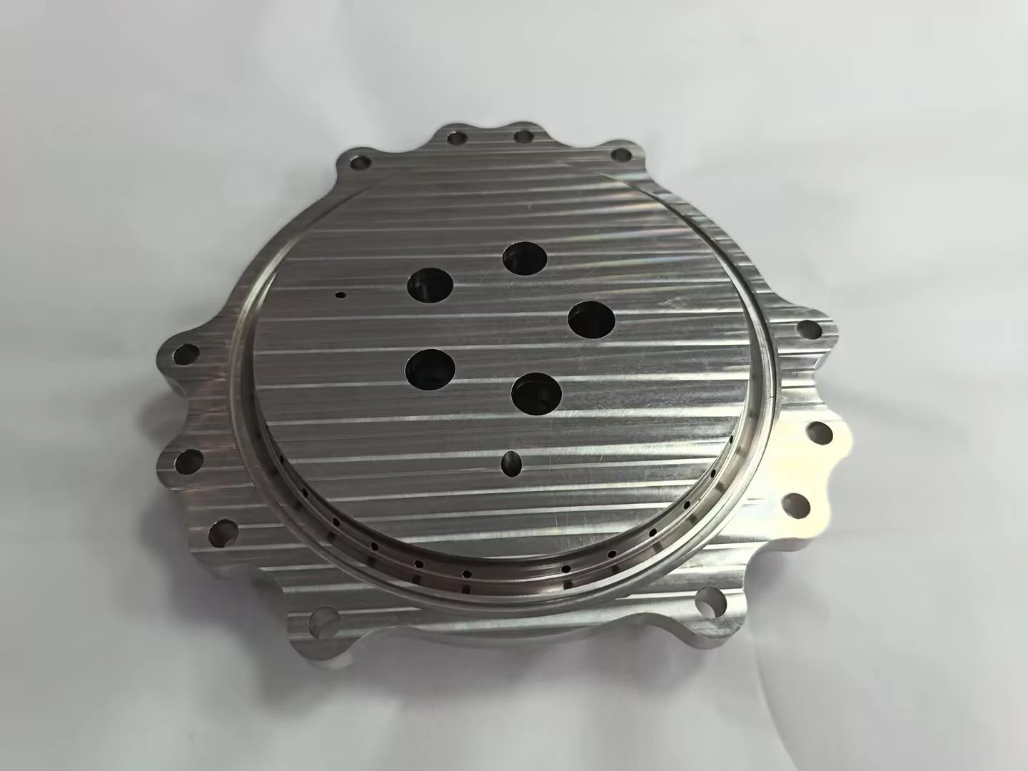 Flat machined plate face with a bolt pattern and a ring of small drilled ports near the rim