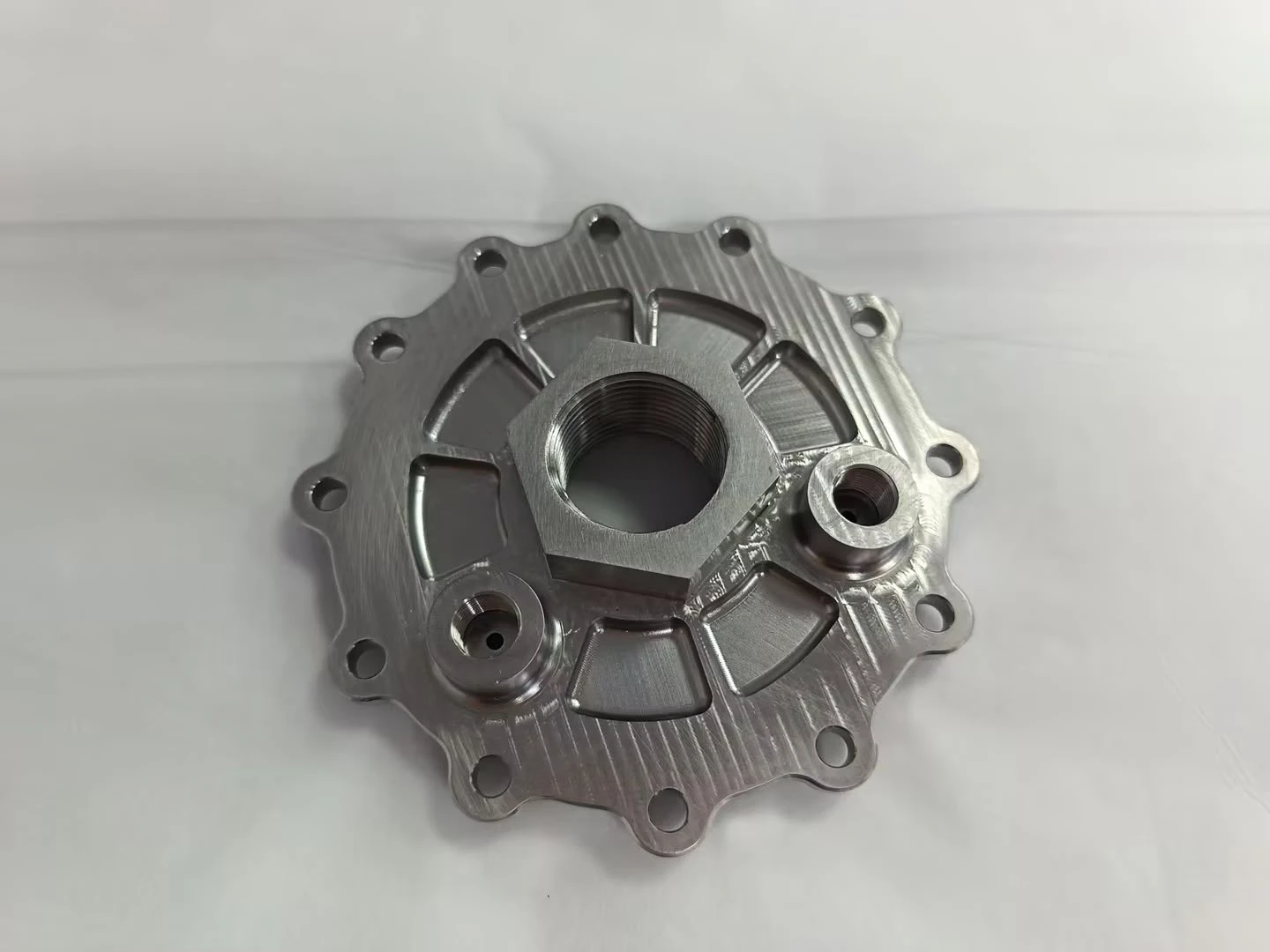 Machined top plate exterior with a central hex boss holding the threaded oxidiser inlet and two smaller instrumentation ports