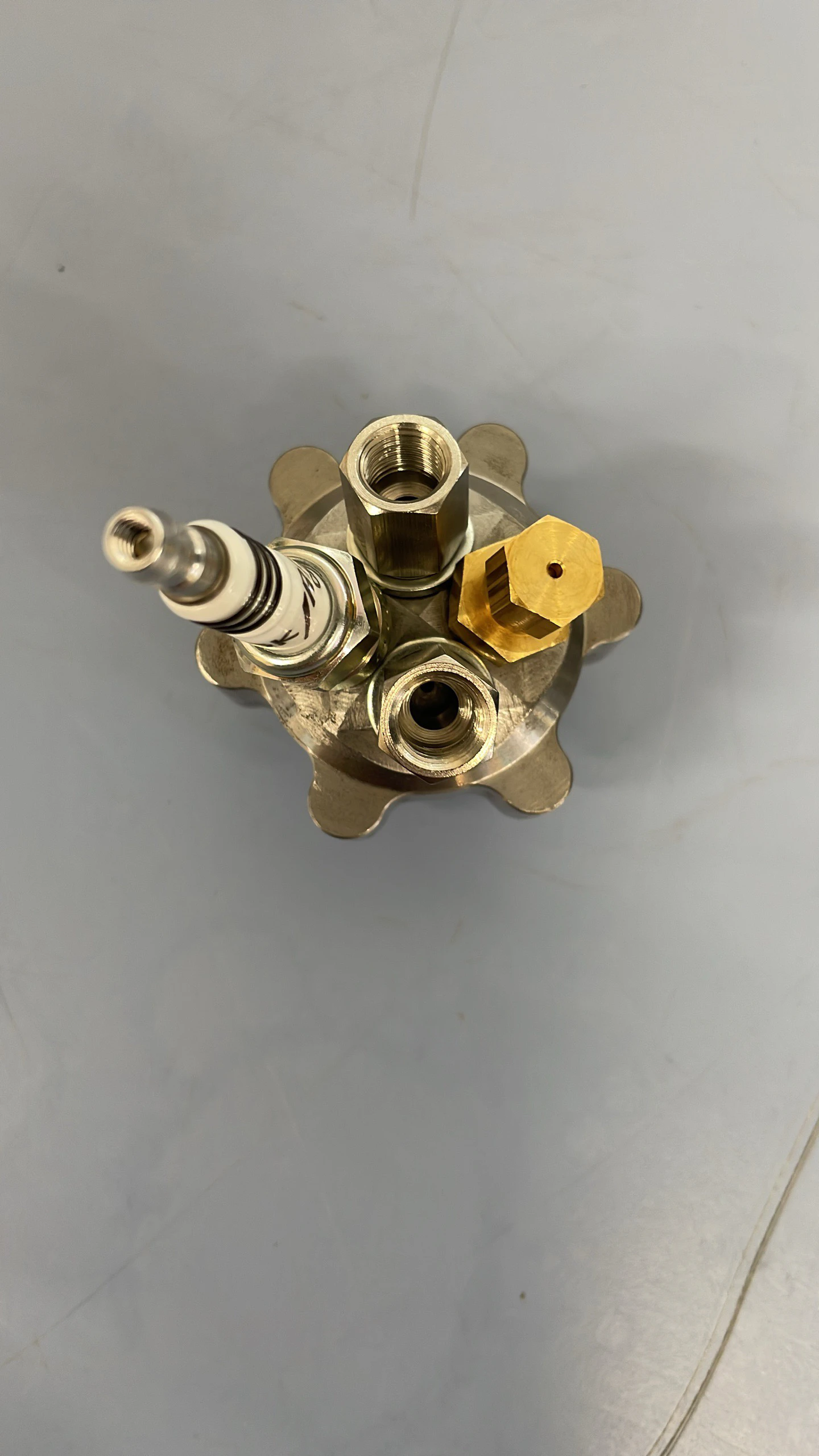 Top-down view of the assembled igniter showing the spark plug and the two brass inlet fittings on the hexagonal steel body.