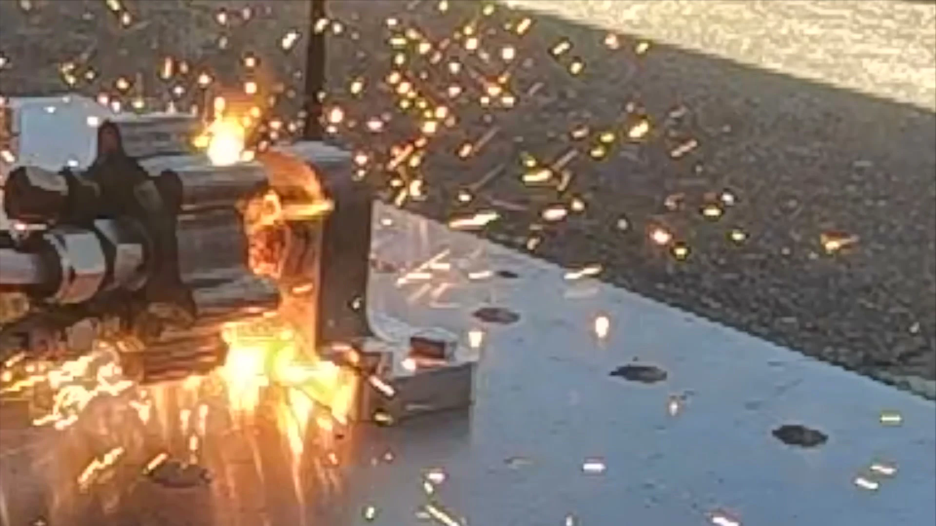 GoPro frame of the igniter engulfed in a spray of bright orange sparks on the test plate.