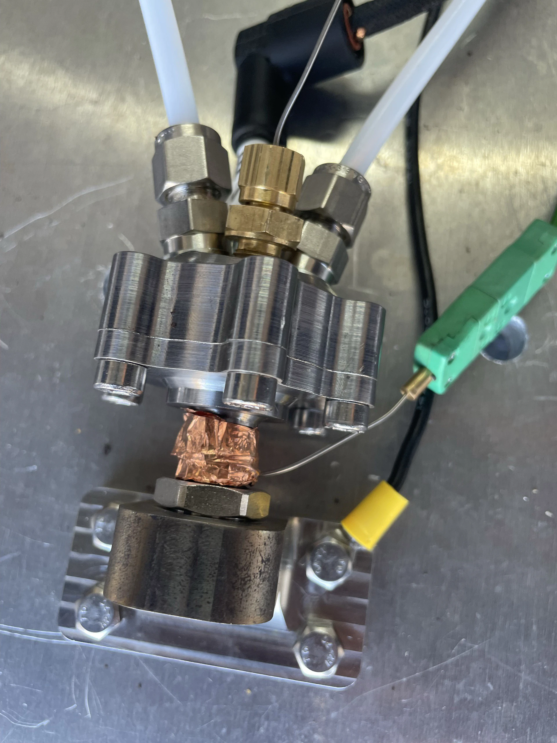 Close view of the mounted igniter with a green thermocouple connector, yellow tape and copper gasket visible.
