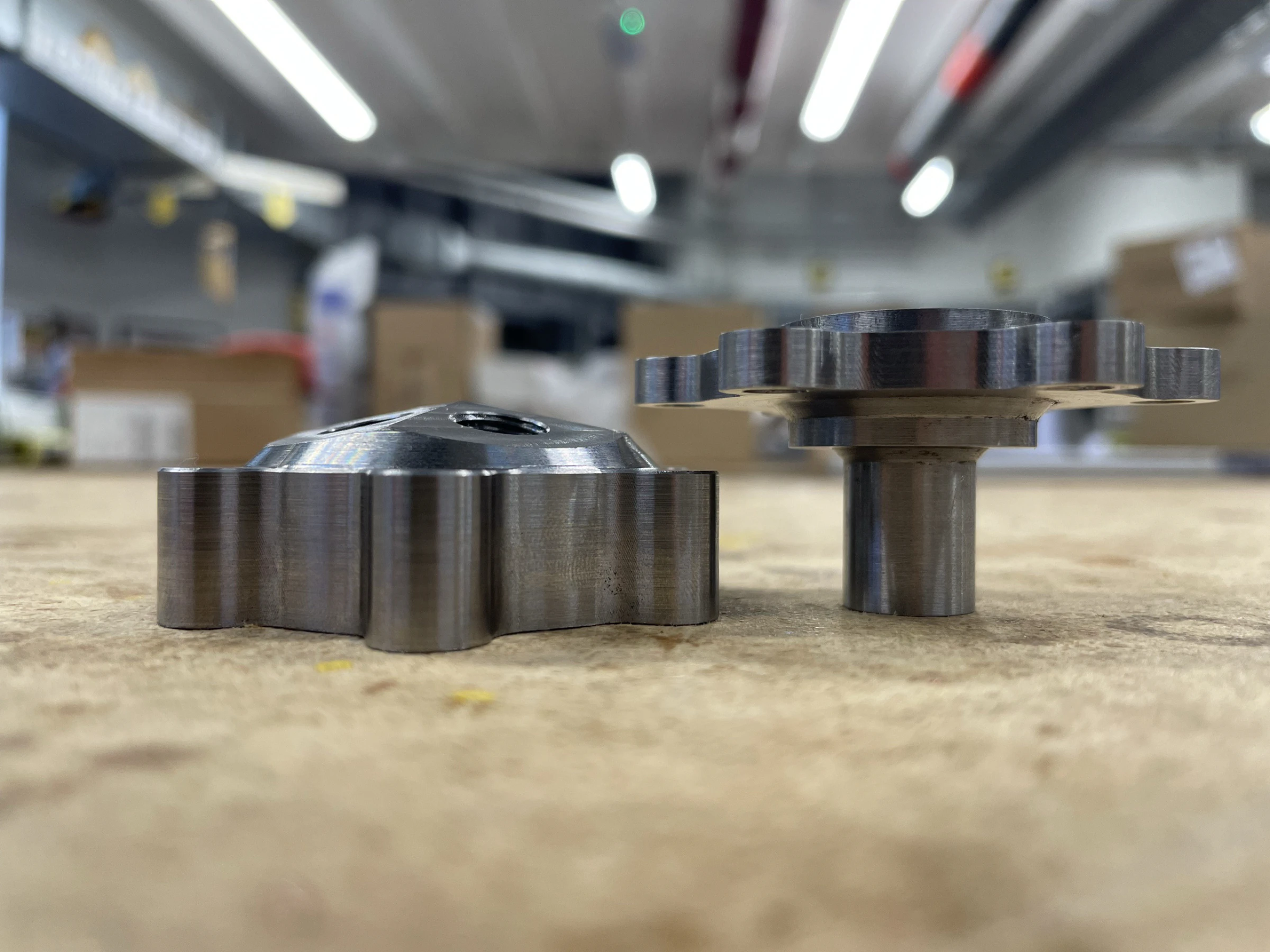 Low bench-level view of the machined igniter parts lined up on a workshop bench.