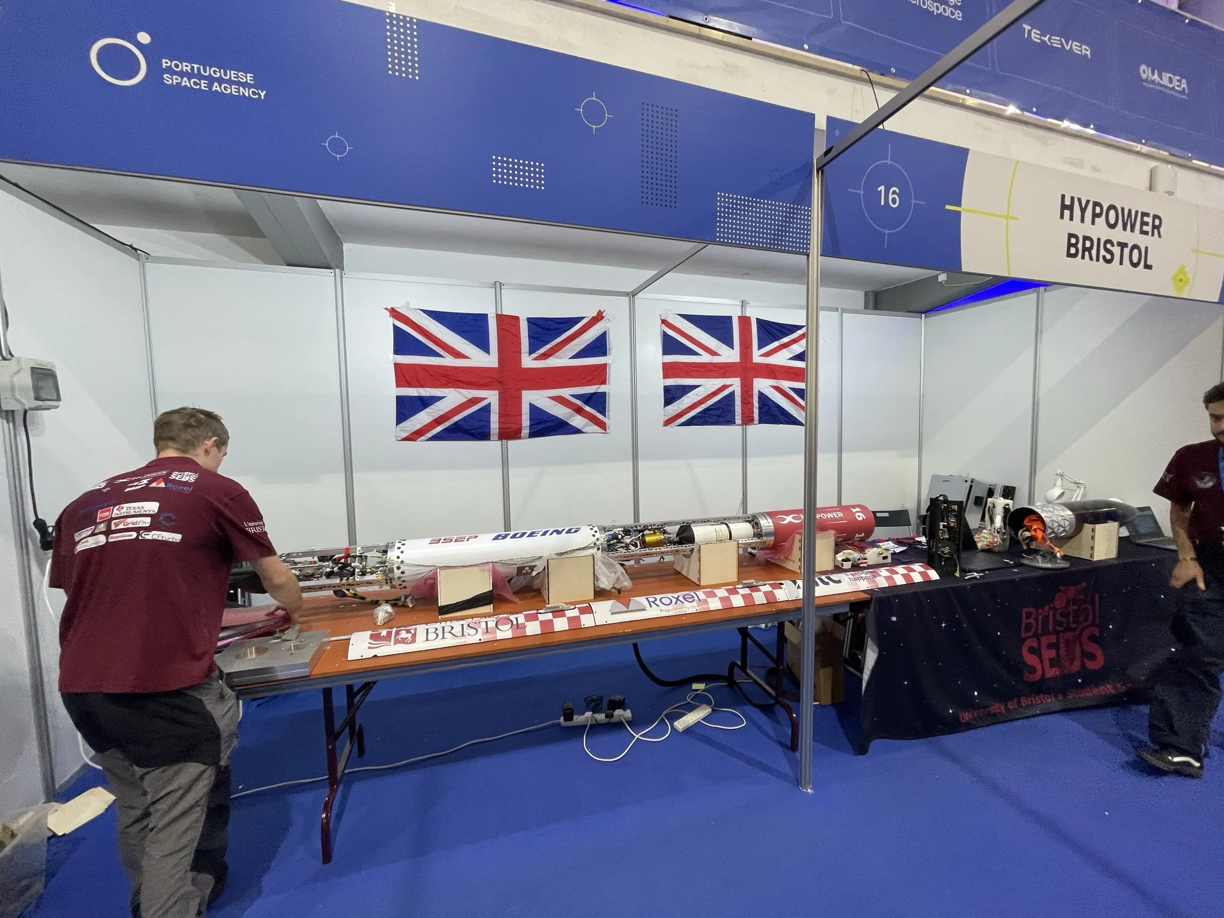 The HyPower Bristol stand at EuRoC, team number 16, with Project Waxwing laid out horizontally in sections on trestle tables under two Union flags and a Portuguese Space Agency banner