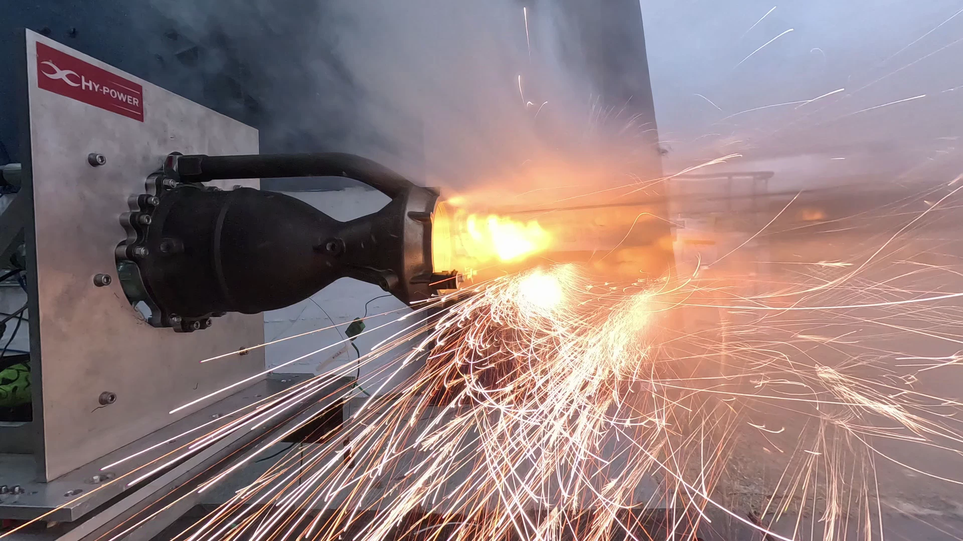 Close on the injector head and nozzle at Hotfire 2 ignition: a bright core at the throat and a fountain of sparks across the plate