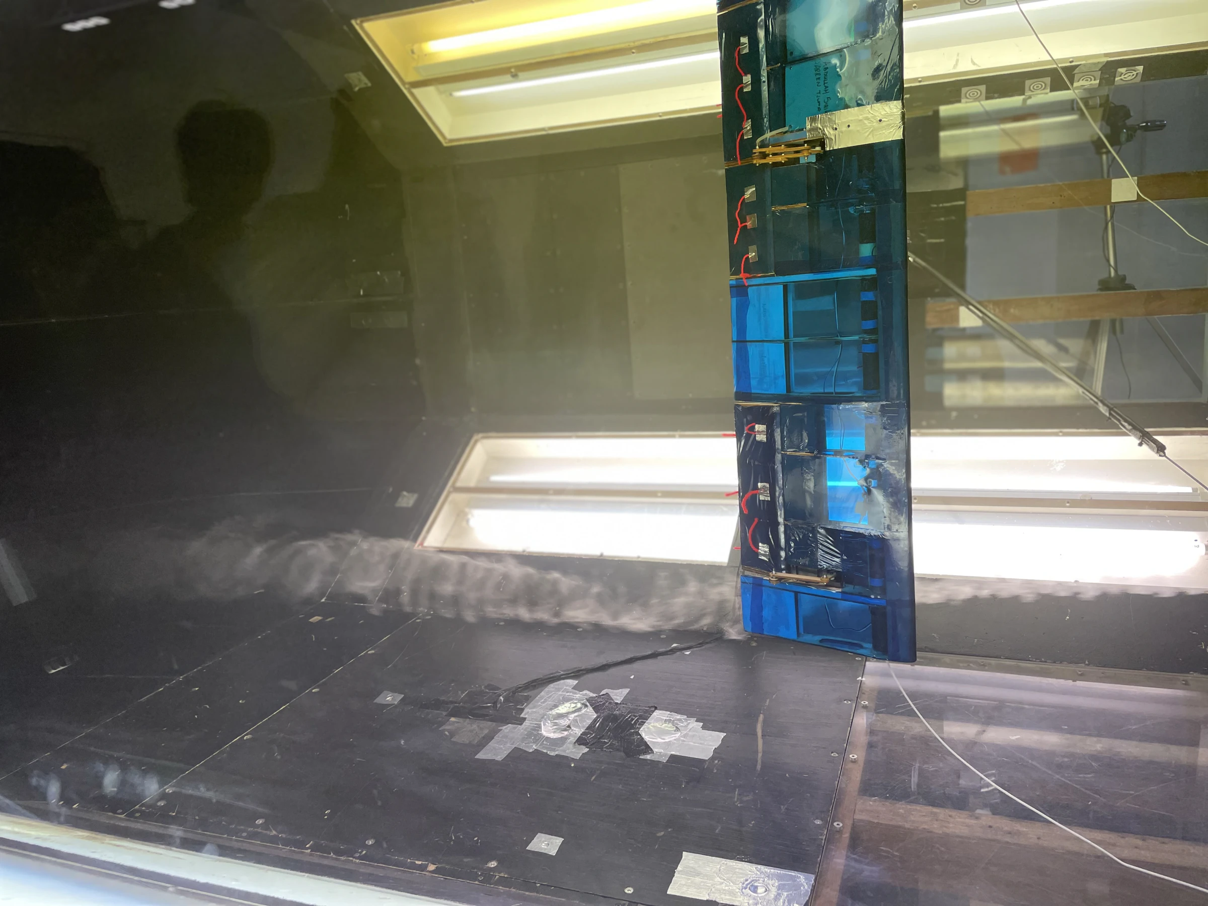 The port wing in the tunnel with the flap deflected, the boundary layer visible as a fuzzy band along the tunnel floor