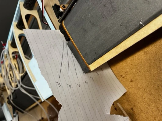 A sheet of lined paper taped under a control surface with deflection angles traced from a protractor and marked in degrees